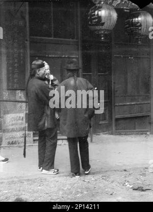 Deux hommes, l'un tenant un enfant, debout dans la rue, Chinatown, San Francisco, entre 1896 et 1906. Banque D'Images