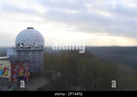 Berlin, Allemagne. 03rd mars 2023. Vu depuis le Teufelsberg de Berlin, le soleil se couche derrière l'horizon sous un ciel couvert et des températures froides. Sur la montagne se trouvent les bâtiments importants d'une station de contrôle et d'écoute de la circulation aérienne dont les bâtiments sont vides et délabrés et sont actuellement utilisés artistiquement. Credit: Felix Hörhager/dpa/Alay Live News Banque D'Images