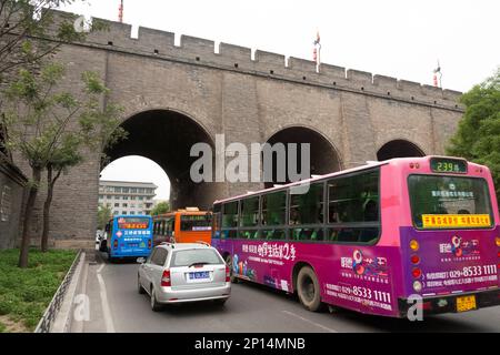 Trafic intense passant par l'arche dans la section fortement restaurée des fortifications de Xi'an incorporant des arches pour les voies d'accès à la ville, également connu comme le mur de la ville de Xi'an à Xi'an. Xian, Chine. PRC. Vue par temps ensoleillé avec ciel bleu pâle. (125) Banque D'Images