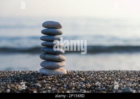 Pyramide de galets équilibrée à la plage. Foyer sélectif Abstract bokeh avec la mer sur l'arrière-plan. Pierres zen sur la plage, méditation, spa, harmonie. Banque D'Images
