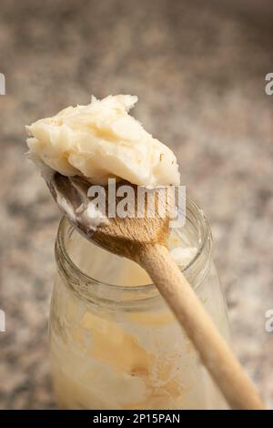 Filet de porc cru sur une cuillère en bois au-dessus du pot en verre dans la cuisine vue rapprochée du dessus. Banque D'Images