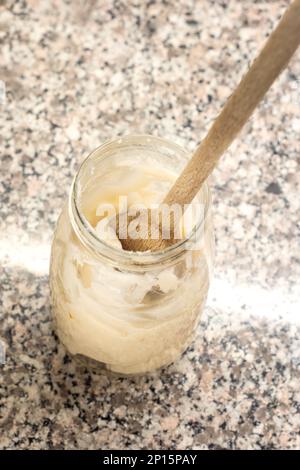 Cuillère de cuisine en bois dans un pot en verre avec un filet de porc cru vue de dessus isolée. Banque D'Images
