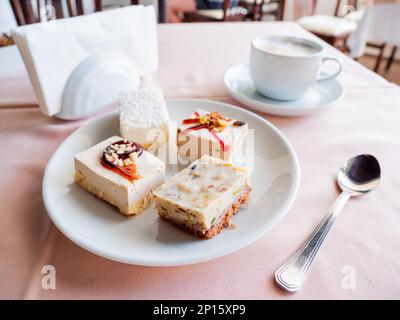 Le petit-déjeuner au café est servi dans une tasse blanche avec cappuccino et assiette de pâtisseries. Desserts savoureux et café chaud. Banque D'Images