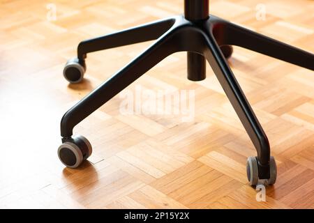 Chaise de bureau en métal noir lags avec roues pivotantes sur plancher de bois carrelage faible profondeur de champ personne. Banque D'Images