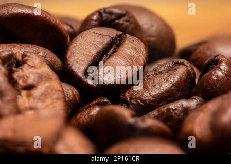 Gros plan sur les grains de café torréfiés bruns a isolé une petite pile de grains en arrière-plan. Banque D'Images