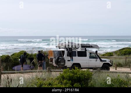 Road trip. Surf van et équipage sur la route voyage avec surf, pêche et équipement de camping et Breaking surf en arrière-plan, Shelly Beach, Tasmanie Banque D'Images