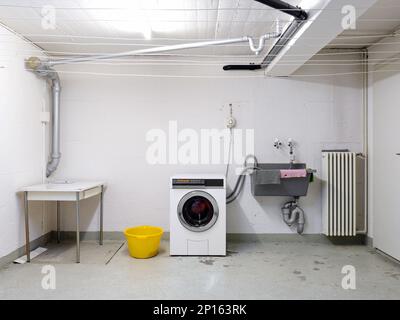 Appartement partagé bâtiment buanderie avec machine à laver dans l'évier usagé et tuyauterie vue grand angle. Banque D'Images