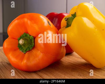 Les poivrons rouges orange et jaunes se sont regroupés sur un plan de cuisine en bois gros plan. Banque D'Images