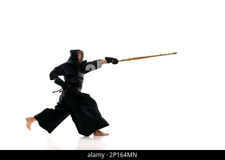 Homme, kendo professionnel athlète en uniforme noir avec épée, shinai entraînement sur fond blanc studio Banque D'Images