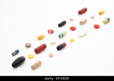 Bouquet de pilules et capsules médicales génériques de couleur variable disposées en rangées isolées sur blanc. Banque D'Images