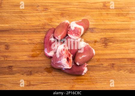 Cœurs de poulet cru regroupés sur une cuisine en bois vue du dessus. Banque D'Images