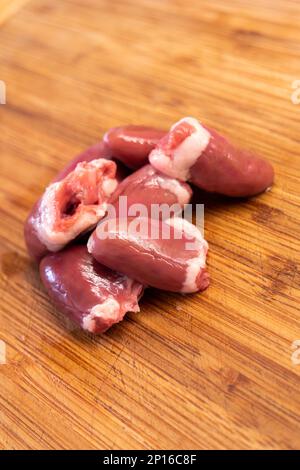 Cœurs de poulet cru regroupés sur une cuisine en bois vue du dessus. Banque D'Images