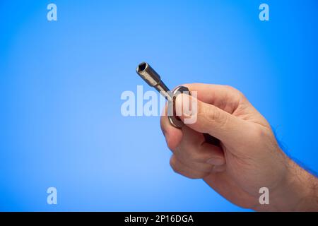 Main mâle caucasienne tenant un vieux panneau d'électricité métallique avec clé de verrouillage prise de vue studio isolée sur fond bleu. Banque D'Images