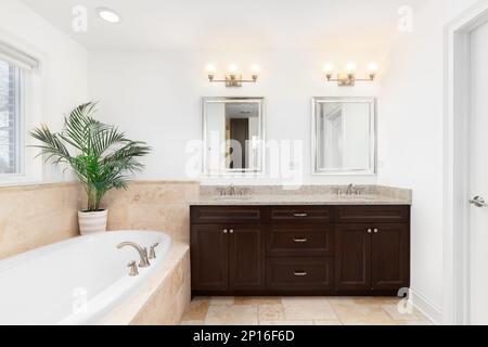 Une salle de bains avec des lumières montées au-dessus de l'armoire en bois, carreaux de céramique Havane, et une grande baignoire. Banque D'Images