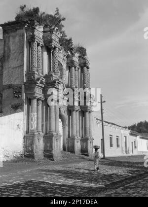 Vues sur Cuba et le Guatemala, entre 1899 et 1926. Fille équilibrant le panier sur sa tête, passant devant une église fortifiée. Banque D'Images