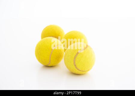 Quatre balles de tennis génériques utilisées studio tir isolé sur fond blanc. Banque D'Images