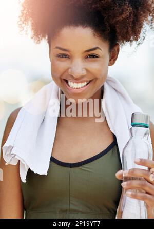 Rester hydraté est essentiel pour votre santé. Coupe courte d'une jeune femme en train de profiter d'une bouteille d'eau pendant qu'elle est dehors pour une course. Banque D'Images