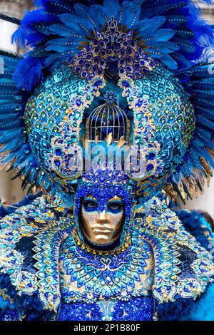 Masque incroyable au carnaval de Venise. Robe d'oiseau recouverte de plumes et de pierres précieuses bleues. différentes nuances de bleu. Banque D'Images