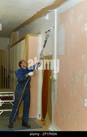 Un peintre applique une couche d'apprêt acrylique sur les murs intérieurs d'un bâtiment de rénovation près de Greymouth, Île du Sud, Nouvelle-Zélande Banque D'Images