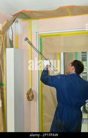 Un peintre applique une couche d'apprêt acrylique sur les murs intérieurs d'un bâtiment de rénovation près de Greymouth, Île du Sud, Nouvelle-Zélande Banque D'Images