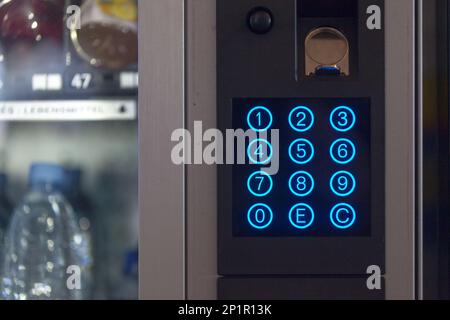 Distributeur automatique qui distribue des en-cas, des bonbons et des boissons avec clavier bleu rétroéclairé. Banque D'Images