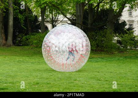 zorbing d'enfant non reconnaissable à l'intérieur de la boule de zorb en plastique transparent dans le parc Banque D'Images