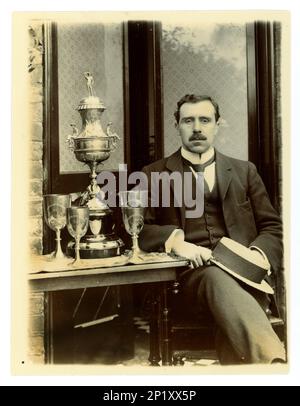 Photo victorienne originale de gent, tenant un bateau. À côté de lui sur une table, il y a un grand vase de défi de Worcester, / régate trophée pour l'aviron, et d'autres coupes, éventuellement membre d'un quatre en boîte équipage. Région de Worcester, Royaume-Uni vers 1897-1899 Banque D'Images