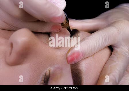 Capture macro de la procédure permanente de maquillage des sourcils, le maître effectue un tatouage sur les sourcils du modèle. Banque D'Images