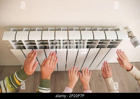 La famille chauffe ses mains près du radiateur. Banque D'Images