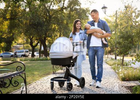 Des parents heureux marchant avec leur bébé dans le parc le jour ensoleillé Banque D'Images