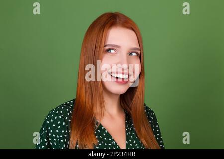 Jeune femme à cheveux rouges sur fond vert sourire et rire, de bonne humeur, émotions positives Banque D'Images