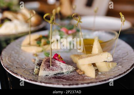 Quatre types de fromages différents tranchés et servis sur une assiette avec une sauce au miel. Banque D'Images