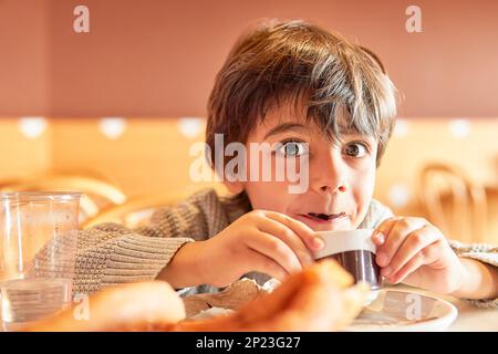 enfant d'âge élémentaire avec moustache en chocolat buvant du chocolat chaud Banque D'Images