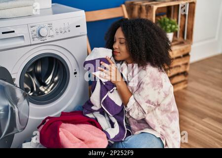 Jeune afro-américaine souriante confiante, lavant des vêtements à la blanchisserie Banque D'Images