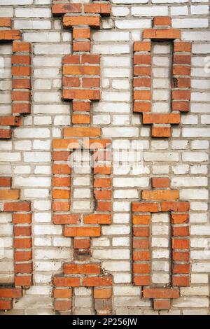 Briques décoratives dans un mur de maison en brique. Motif géométrique orange sur fond gris Banque D'Images