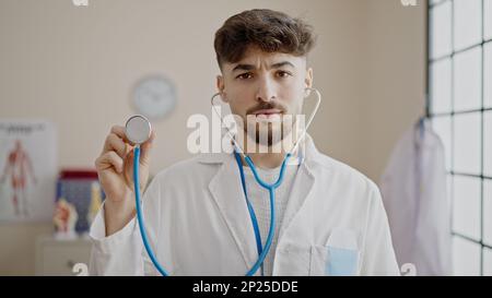 Jeune homme arabe médecin tenant le stéthoscope à la clinique Banque D'Images