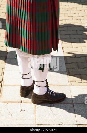 Le rouge et le vert écossais tartan kilt. Highlander portant des vêtements traditionnels de l'Écosse. Cornemuse uniforme - jupe et chaussettes Banque D'Images