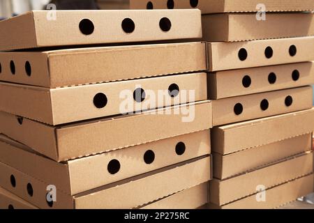 Deux piles de nouvelles boîtes à pizza fermé avec des trous. De nombreux cartons d'aliments vides télévision dans une pile. Beaucoup d'emballage brun dans un restaurant à emporter Banque D'Images