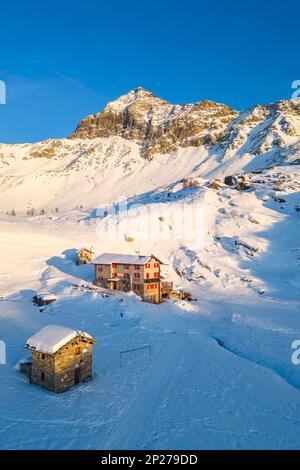 Coucher de soleil devant Rifugio Cristina et Pizzo Scalino en hiver. Lanzada, Valmalenco, Valtellina, quartier de Sondrio, Lombardie, Italie, Europe. Banque D'Images