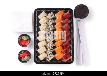 Set de sushi avec wasabi, gingembre et sauce soja servi dans une boîte en plastique à emporter, à emporter. Assortiment de sushis japonais avec thon, saumon, sésame isolé sur wh Banque D'Images