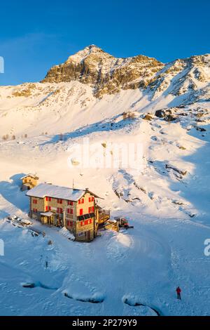 Coucher de soleil devant Rifugio Cristina et Pizzo Scalino en hiver. Lanzada, Valmalenco, Valtellina, quartier de Sondrio, Lombardie, Italie, Europe. Banque D'Images