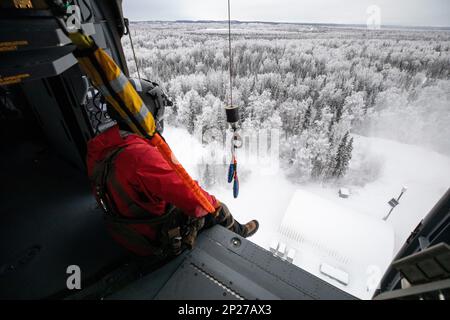 Les gardes de l'Armée de l'Alaska, avec le détachement 2, 2-211th général appui Aviation Bataillon, aident les aviateurs de tactiques spéciales, affectés à la 24th Escadre des opérations spéciales, détachement 1, avec une évacuation médicale et une formation de palan au Camp Mad Bull sur la base interarmées Elmendorf-Richardson, Alaska, le 10 janvier 2023. Le bataillon de soutien général de l’aviation de la Garde nationale de l’Armée de l’Alaska s’entraîne régulièrement avec toutes les branches de l’armée et les organismes civils pour accroître son interopérabilité opérationnelle et être prêt à accueillir une vaste gamme de missions fédérales et d’État. Banque D'Images