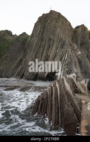 Vue sur les couches fortement inclinées de la formation géologique du flysme sur la côte atlantique à Zumaia à marée basse, pays basque, Espagne Banque D'Images