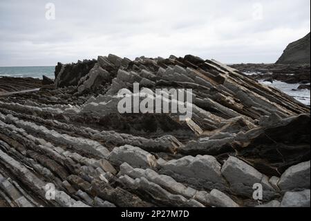 Vue sur les couches fortement inclinées de la formation géologique du flysme sur la côte atlantique à Zumaia à marée basse, pays basque, Espagne Banque D'Images