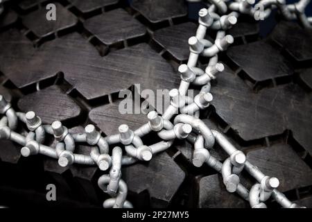 Nouvelles chaînes pour pneus cloutés propre close-up. Roue noire enveloppée dans des chaînes à neige d'argent Banque D'Images