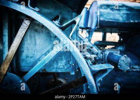 Tracteur Antique roue à pointes de métal close-up. Vintage acier agricole machine. Arrière-plan bleu techno industrielle Banque D'Images