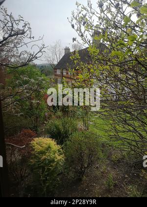 Vue sur un jardin de campagne avec une ferme au loin. Banque D'Images