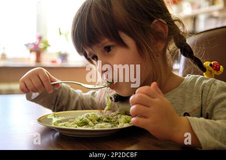 Petite fille mangeant de la salade de chou. La fille coupée aime la salade de chou. Une alimentation saine Banque D'Images