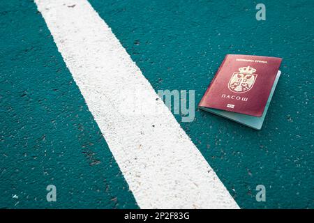 Passeport national serbe à côté d'une ligne blanche au sol. Symbolique, frontière Banque D'Images