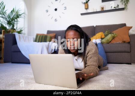 Femme noire indépendante travaillant sur un ordinateur portable à la maison. Banque D'Images